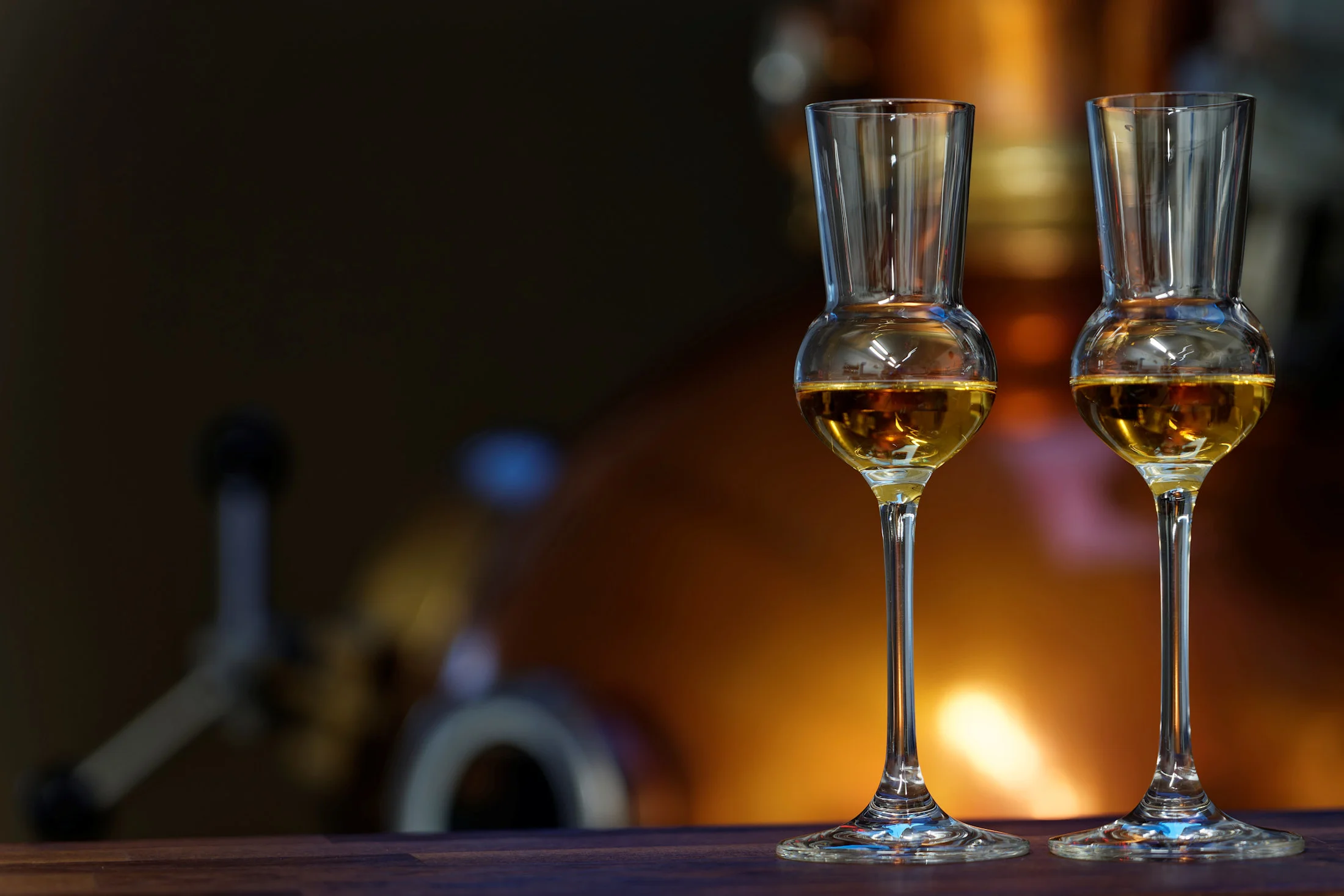 zwei gefüllte Grappa - Gläschen vor verschwommenem Hintergrund