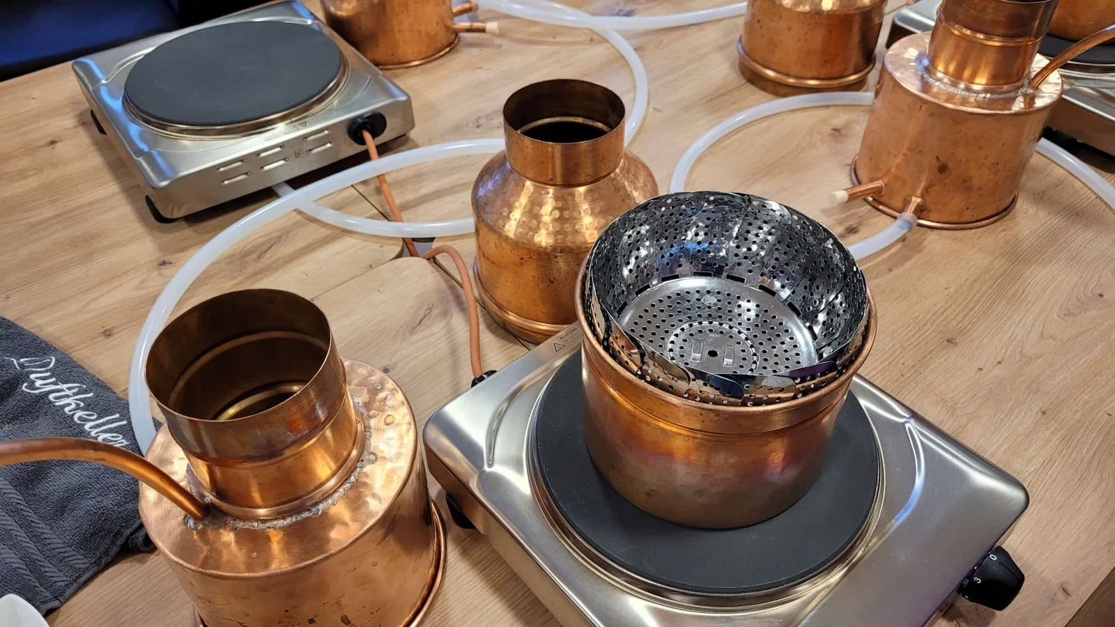 Die Kupferkessel werden erhitzt, während die Botanicals für die Destillation von ätherischen Ölen sorgfältig vorbereitet werden.